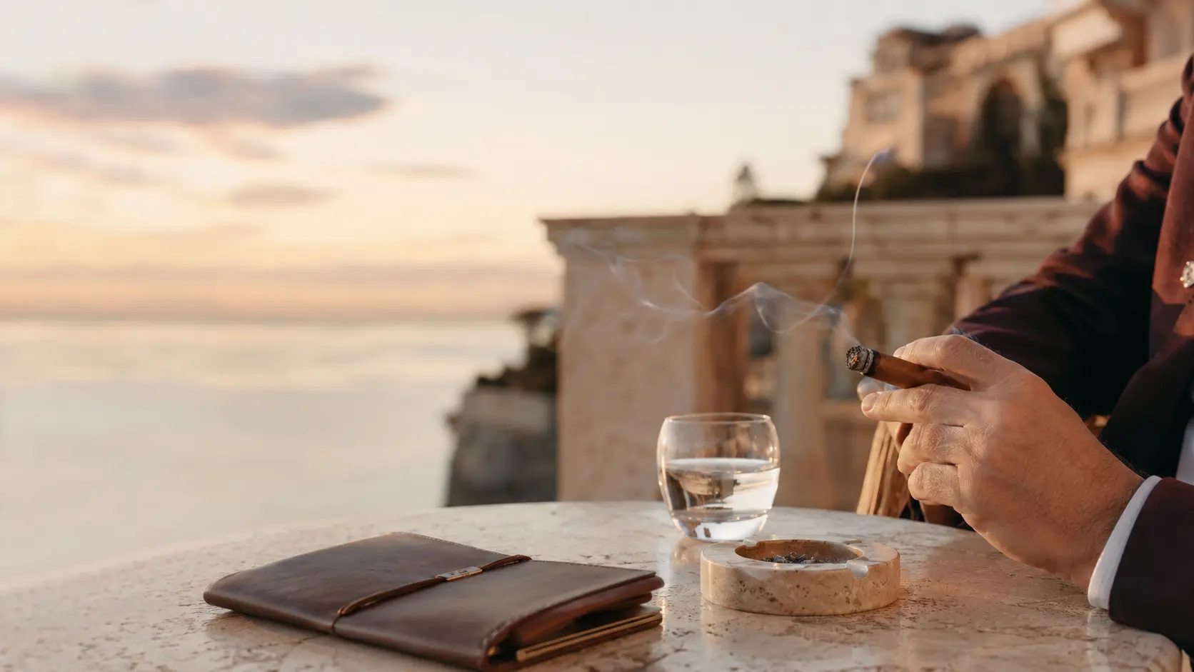 Un amateur tenant un cigare Monte-Carlo Club® sur une terrasse face à la Méditerranée.